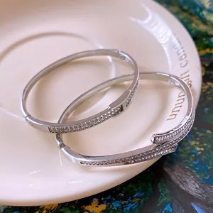 Silver zircon H-buckle bracelet set and interlocking bangle on a ceramic tray