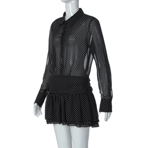 Dettaglio di abito nero in chiffon a pois bianchi, colletto polo e orlo plissettato
