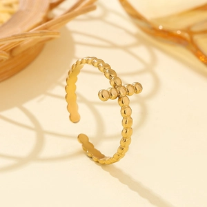 Macro shot of gold-plated stainless steel ring with a cross design made of small beads