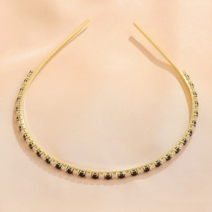Detail of emerald green cross headband with sparkling black and clear gemstones on gold metal
