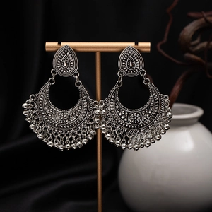 Detail of vintage silver boho earrings with hollow carving and tassels on display