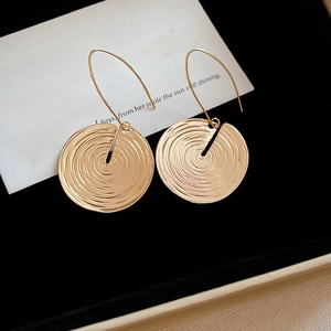 Macro view of gold round spiral textured earrings on a white card background