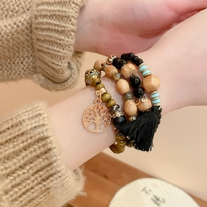 Detailed view of multilayer sandalwood beads with Life Tree charm and black tassel fringe