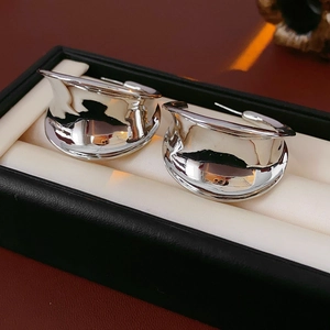 Macro shot of silver wide-band C-shape earrings with a polished mirror finish in a box
