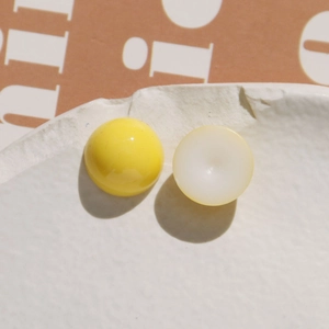Macro shot of smooth yellow and white resin dome charms for DIY craft making