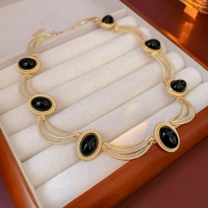 Close-up of vintage gold necklace with oval black gemstones inside a wooden jewelry box
