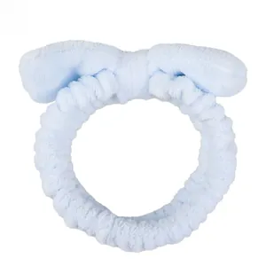 Close-up of soft light blue coral fleece headband with a large bow for skincare