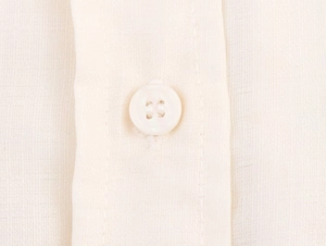 Gros plan sur le bouton beige et le tissu texturé de cet ensemble décontracté à rayures