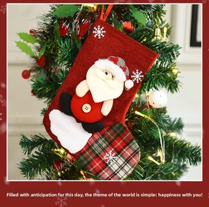 Detail of red linen Christmas stocking with 3D Santa Claus hanging on festive tree