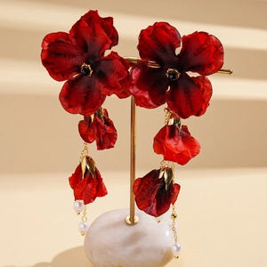 Details von roten Stoffblumen-Ohrringen mit goldenen Akzenten und eleganten Perlen