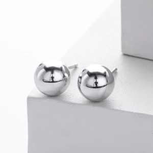 Macro shot of polished S925 sterling silver ball stud earrings on a white stone base