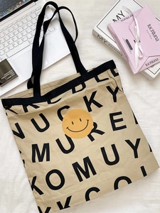 Khaki canvas tote bag with yellow smiley face and letter print on casual lifestyle background