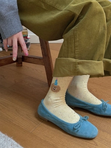 Close-up of cream socks featuring cartoon bear embroidery and colorful speckle texture