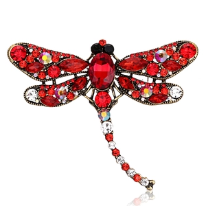 Detailed close-up of vintage dragonfly brooch featuring red rhinestones and bronze frame