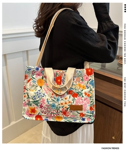 Detail of floral canvas tote bag showing colorful print and brown leather fashion label