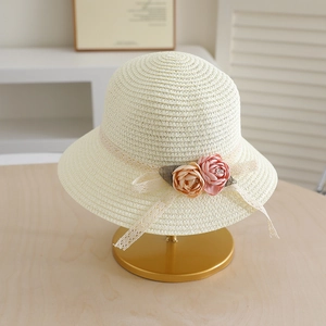 Detail of cream straw hat featuring delicate lace ribbons and handmade floral accents