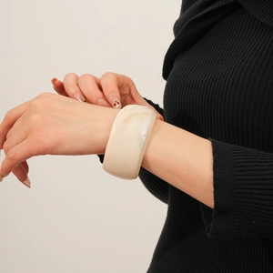 Close-up of minimalist cream resin wide bangle with subtle marble texture on a model