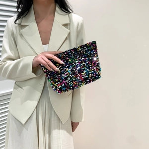 Fashionable rectangular handbag with colorful sequins held by a model in a beige suit