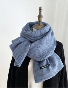 Detail of blue knitted checkerboard scarf showing the soft texture and brand label