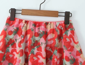 Dettaglio della gonna in chiffon con stampa di fragole e un piccolo fiocco rosa in vita