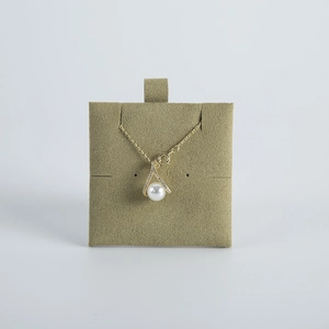 Detail of a pearl pendant necklace with V-shaped zircon clasp on a green velvet display board