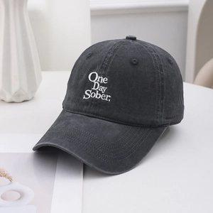 Detail of white One Day Sober embroidery on a vintage washed dark grey baseball cap