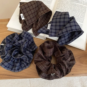 Detailed close-up of plaid fabric hair scrunchies on vintage book and wooden surface
