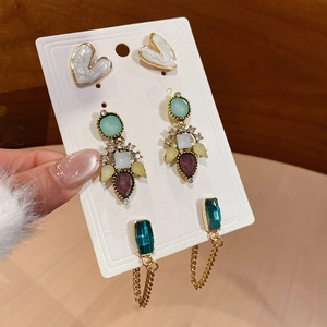 Detailed macro view of vintage resin heart studs and colorful gemstone dangle earrings