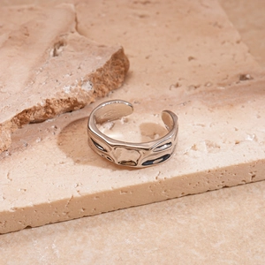 Close-up of irregular textured silver open ring on beige natural stone display