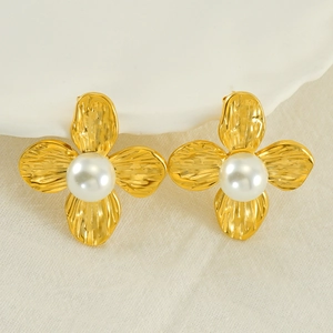 Macro view of gold flower earrings with hammered texture and a central white pearl