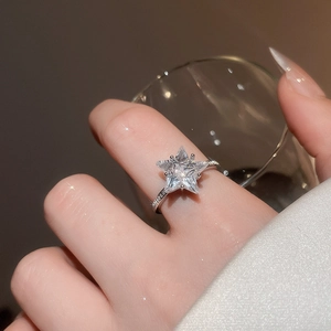 Detail of a sparkling star-shaped zircon ring with silver-tone band worn on a finger