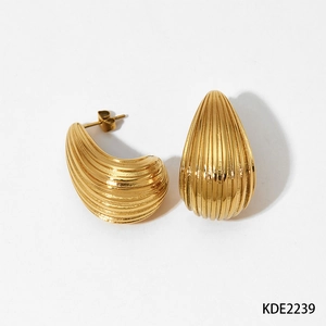 Close-up of golden teardrop earrings with textured vertical stripes and metallic finish