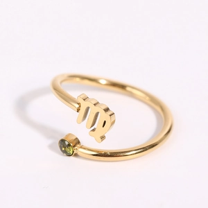 Detailed shot of golden zodiac open ring featuring Virgo symbol and a green gemstone