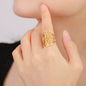 Detail of gold hollow ring with eye and star patterns on a model's finger