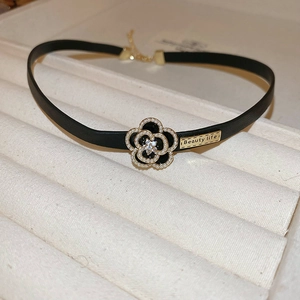 Détail d'un choker en cuir floral noir avec perle et strass sur plateau en velours