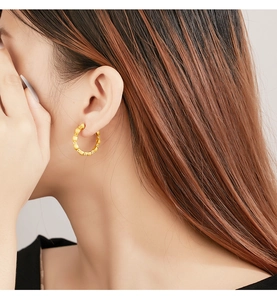 Close-up of model wearing vintage brushed gold hoop earrings with twisted texture