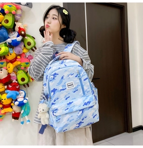Detail of blue camouflage school backpack with fashion tag and cute bear pendant