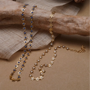 Floral enamel daisy choker necklace with gold beads on rustic wood and burlap background