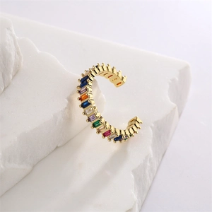 Close-up of gold-plated ear cuff with multi-colored zircons on a textured stone
