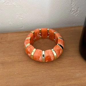 Détail du bracelet en résine marbrée orange avec intercalaires dorés sur bois