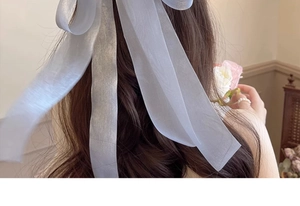 Large light blue organza ribbon hair bow clip shown on long wavy hair from behind