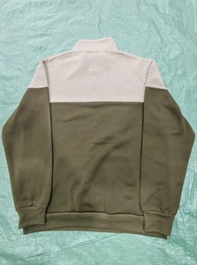 Detail of waffle knit sweatshirt showing beige quilted top and olive green paneling