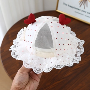 Détail d'un chapeau de soleil pour bébé en coton blanc avec motifs cœurs et dentelle