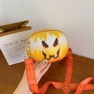 Detail of pumpkin-shaped crossbody bag with spooky face and gold chain strap