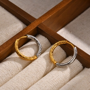 Macro detail of gold and silver quilted pattern hoop earrings in a jewelry box