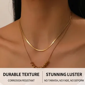 Close-up of dual-layer gold plated snake chain necklace with small beaded details