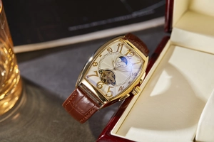 Detail of tonneau mechanical watch with sun-moon phase and leather strap on a box