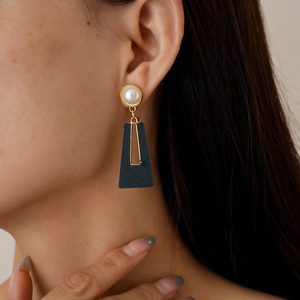Detail of vintage acrylic faux pearl earrings with black trapezoid drop worn by a model
