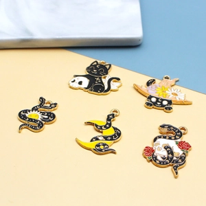 Macro shot of dark gothic enamel charms featuring a black cat, snake, skull and crescent moon