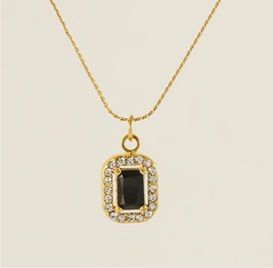 Macro detail of gold square pendant featuring a black gemstone and crystal pavé edge